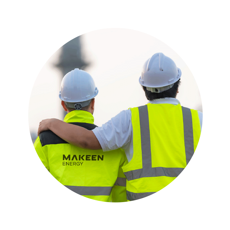 two workers from behind, both wearing white safety helmets and yellow safety jackets